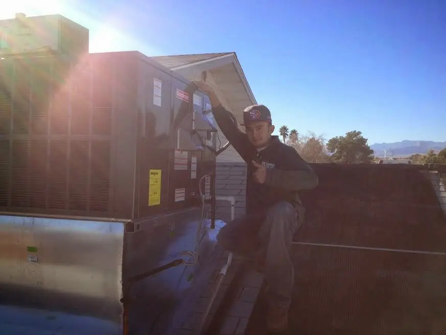 HVAC technician performing AC Tune-Up on a rooftop unit in Evansville